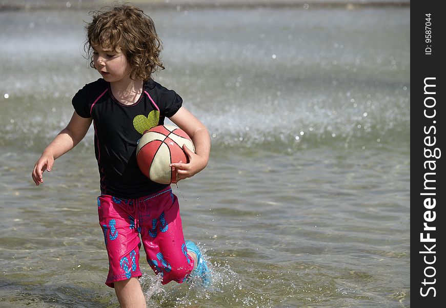 This young girl is busy playing in this paddling pool with her ball. This young girl is busy playing in this paddling pool with her ball.