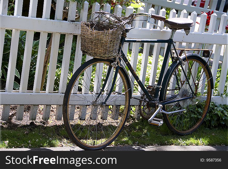 Old rusty bike leaned to the white fence