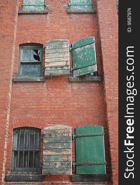 Old grungy abandoned brick building with falling shutters. Old grungy abandoned brick building with falling shutters