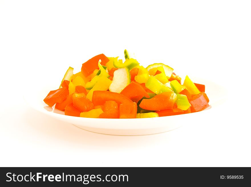 Red,Green and yellow chopped peppers on a plate on a white background
