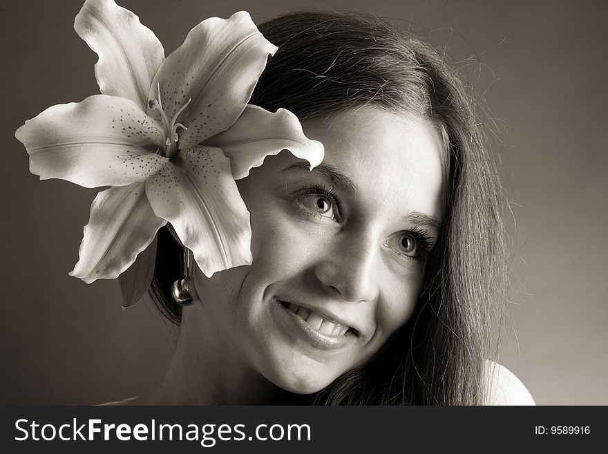 A pretty young woman with long hair posing with a lily near her face. A pretty young woman with long hair posing with a lily near her face