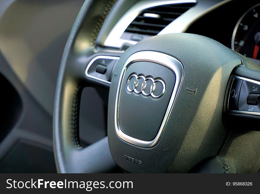 Close up of Audi logo on leather steering wheel automotive interior. Close up of Audi logo on leather steering wheel automotive interior.