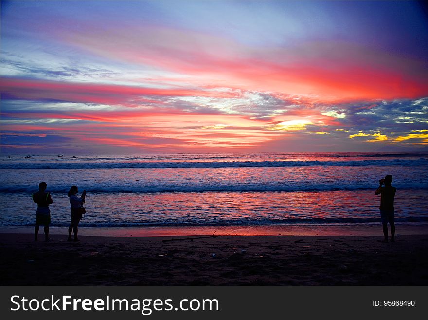 Silhouette of people standing on sandy Bali beach at sunset. Silhouette of people standing on sandy Bali beach at sunset.