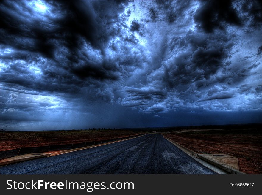 Dark clouds above a remote straight road. Dark clouds above a remote straight road.