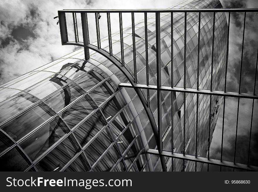 A black and white photo of a futuristic glass skyscraper with a metal gate.