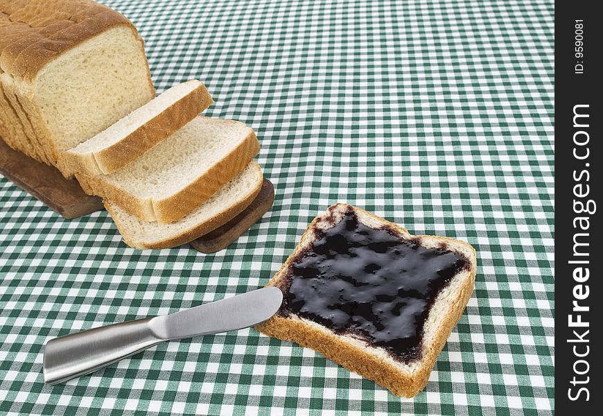 A slice of bread spread with jam beside the loaf of bread. A slice of bread spread with jam beside the loaf of bread.