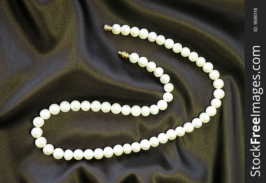 Natural white pearls necklace on brown satine