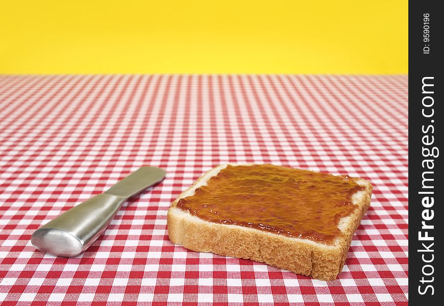 A slice of bread spread with jam and a knife over the table. A slice of bread spread with jam and a knife over the table.