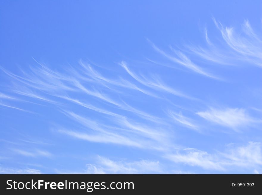 Thin, whispy clouds forming an unusual pattern against a medium-blue sky. Thin, whispy clouds forming an unusual pattern against a medium-blue sky