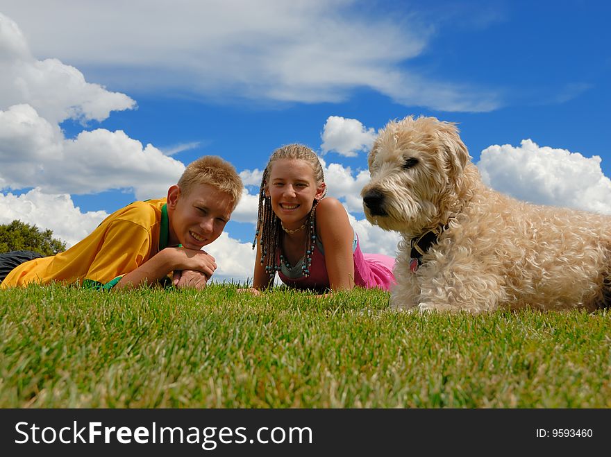 Brother and sister laying on grass with their wheaten terrier dog. Brother and sister laying on grass with their wheaten terrier dog.