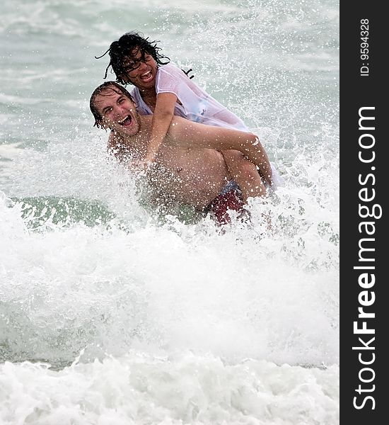 Couple having fun in the water. Splashing waves. Couple having fun in the water. Splashing waves.