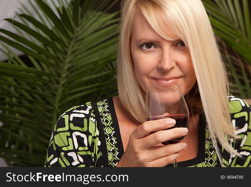 Beautiful blonde smiling woman at an evening social gathering tasting wine. Beautiful blonde smiling woman at an evening social gathering tasting wine.