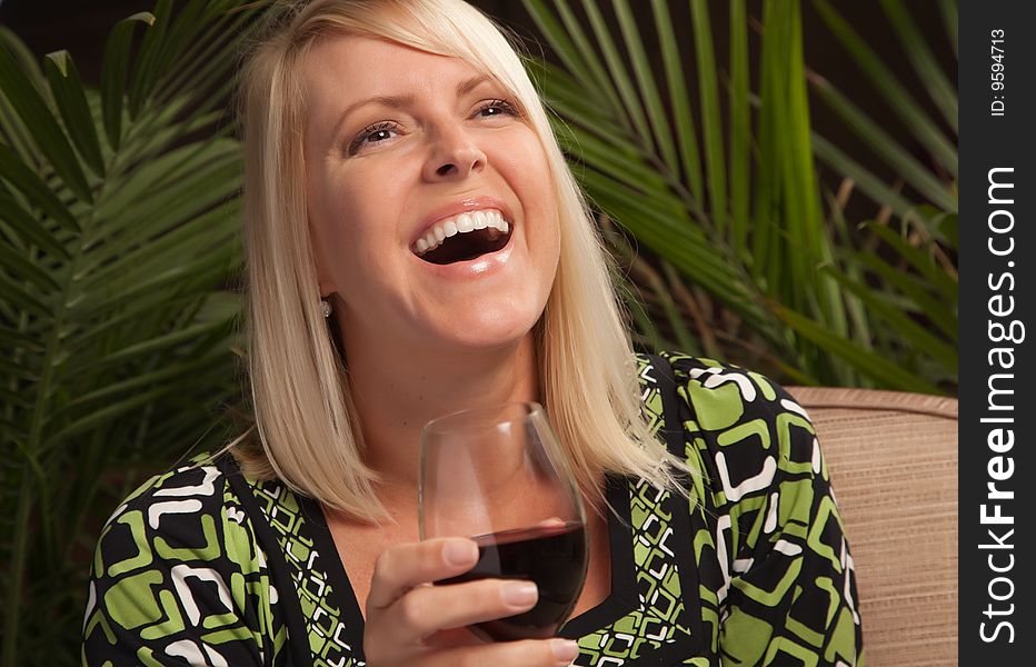 Beautiful blonde smiling woman at an evening social gathering tasting wine. Beautiful blonde smiling woman at an evening social gathering tasting wine.