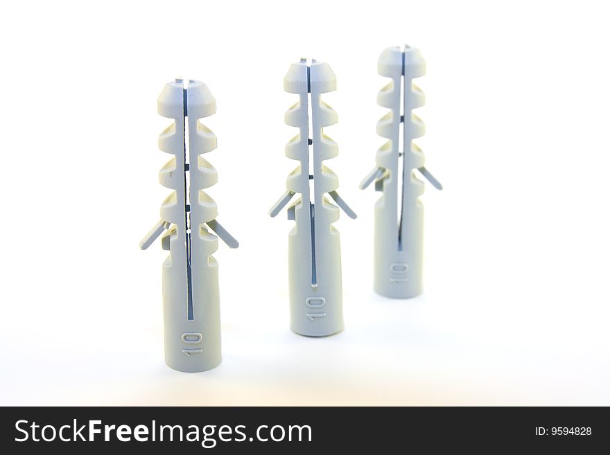 Three grey plastic wall plugs in a row on a white background. Three grey plastic wall plugs in a row on a white background