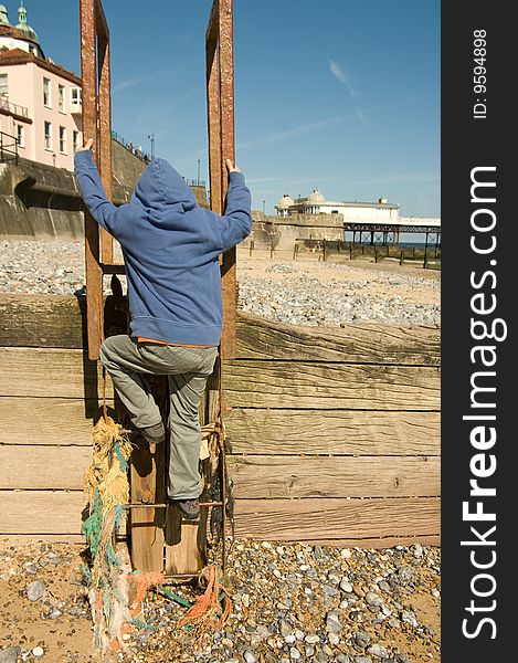 A boy climbs a ladder on Cromer beach with the pier in the background. A boy climbs a ladder on Cromer beach with the pier in the background