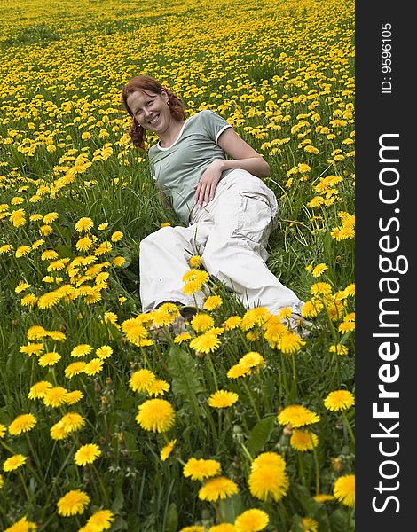 Young lady sitting in the meadow of dandilions. Young lady sitting in the meadow of dandilions