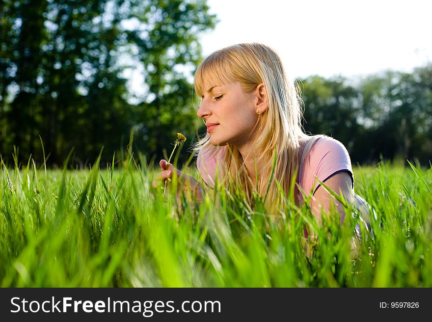 Beautiful blonde girl smells a dandelion