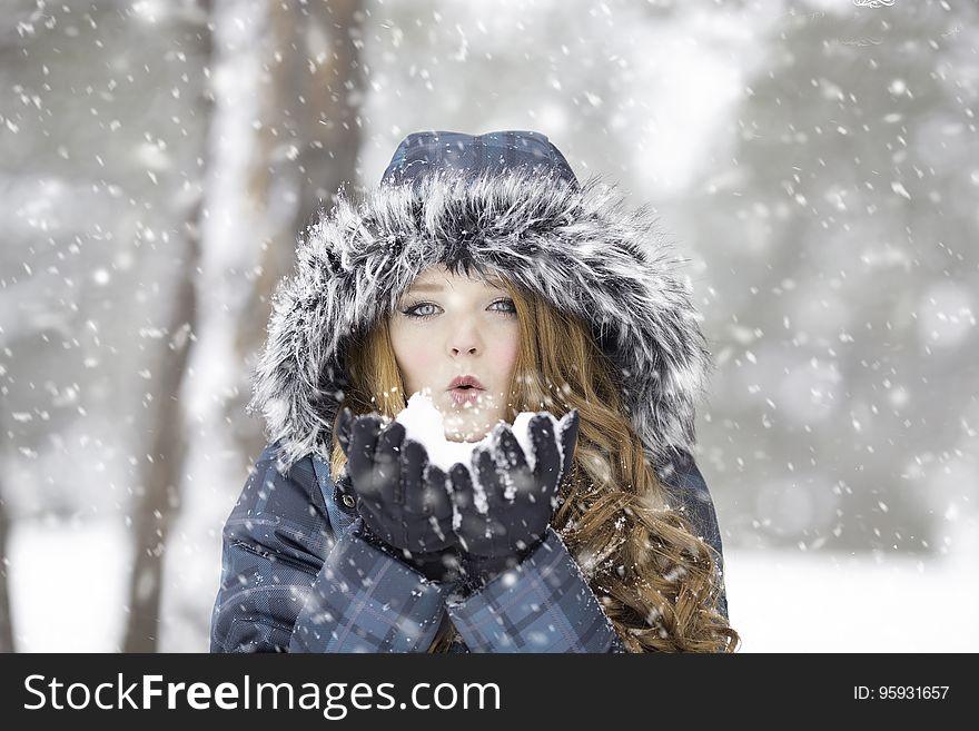 Portrait of pretty blond woman in warm jacket with fur hood posing in a snow storm. Portrait of pretty blond woman in warm jacket with fur hood posing in a snow storm.