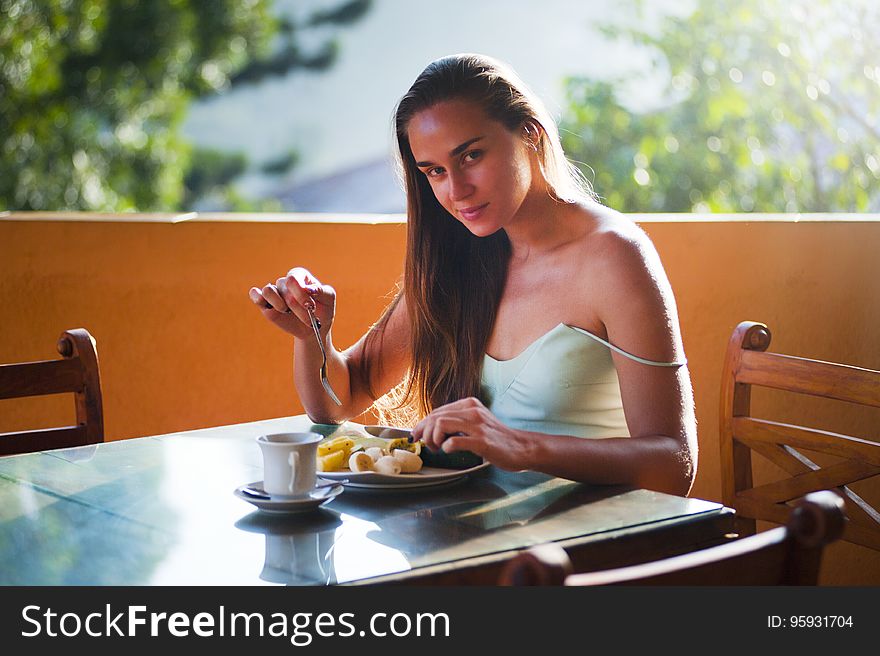 Portrait of woman seated at outdoor table eating meal. Portrait of woman seated at outdoor table eating meal.