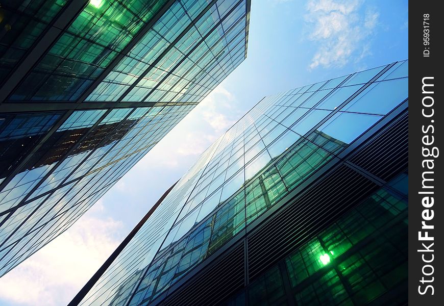 Glass and steel modern architecture from low angel against blue skies with white clouds. Glass and steel modern architecture from low angel against blue skies with white clouds.