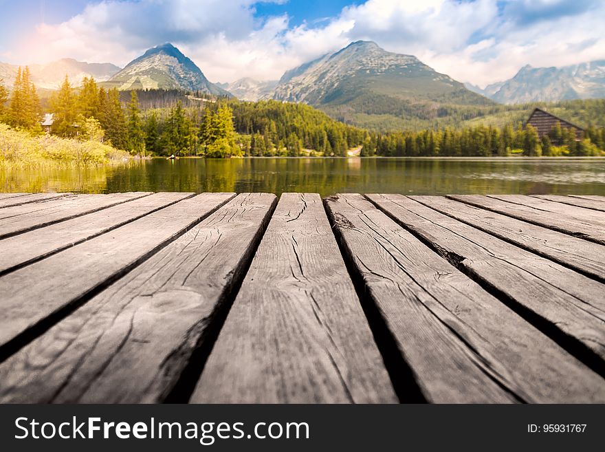 Scenic view of lake, forest and mountains with wooden pier in foreground. Scenic view of lake, forest and mountains with wooden pier in foreground.