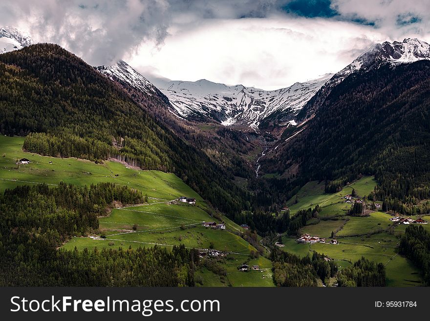 Town in green fields of mountain valley with fog or clouds. Town in green fields of mountain valley with fog or clouds.