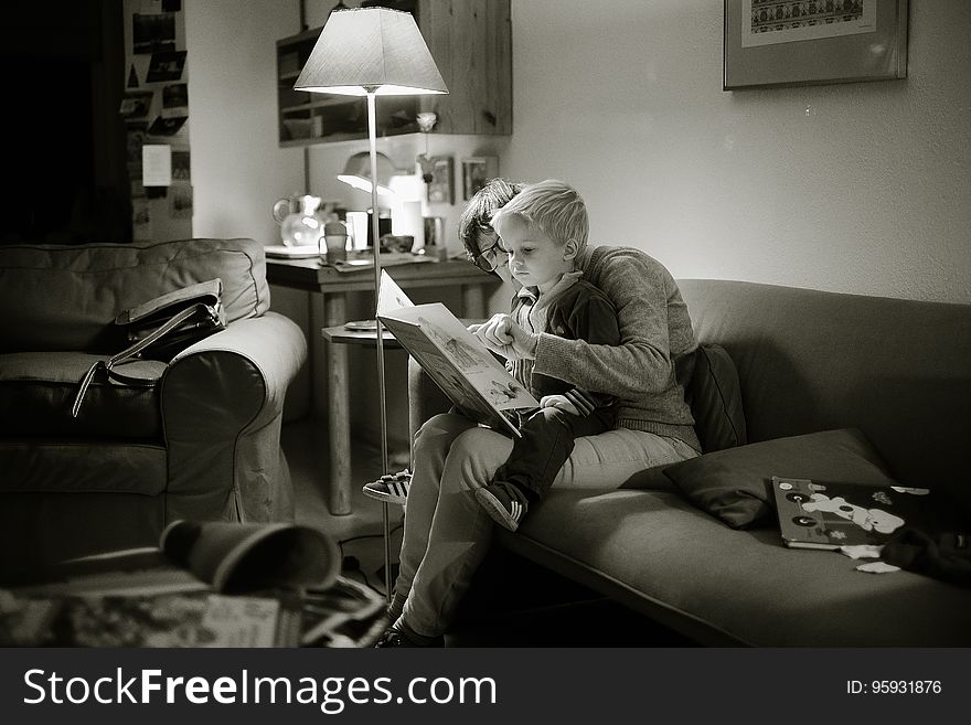A woman reading with a baby on the sofa. A woman reading with a baby on the sofa.