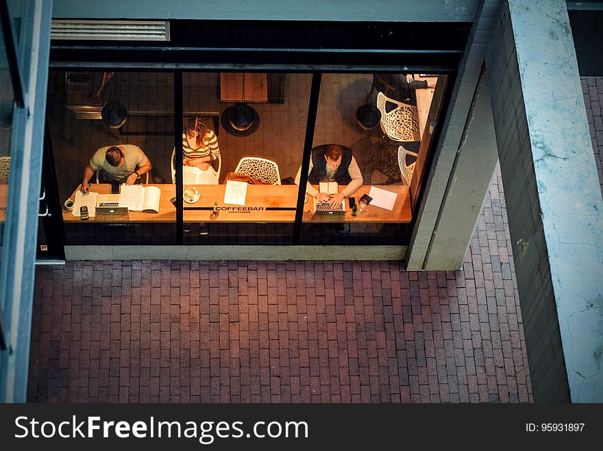 A high angle view through the window of a coffee shop with people sitting inside. A high angle view through the window of a coffee shop with people sitting inside.
