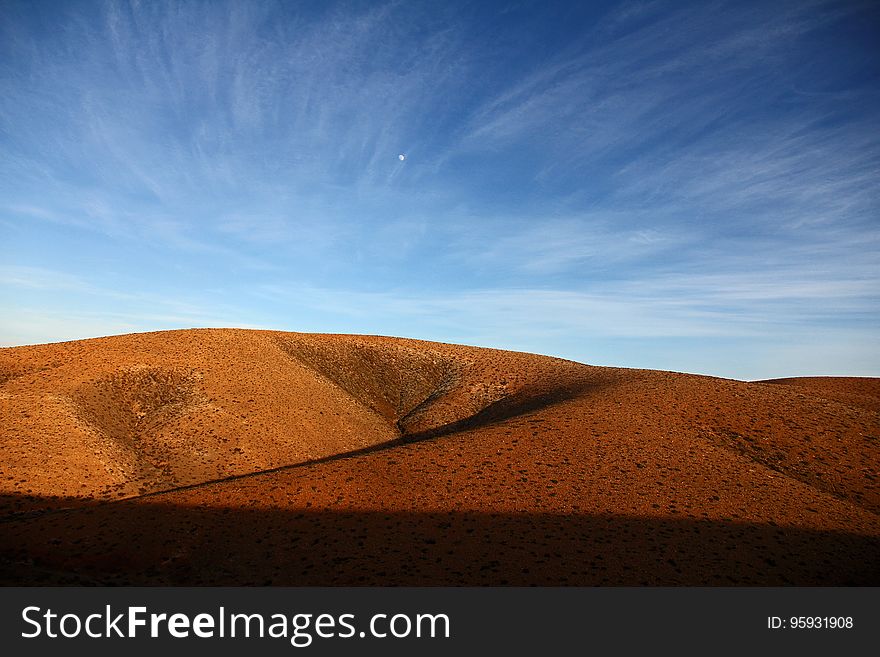 A landscape with dry red hills and blue skies.