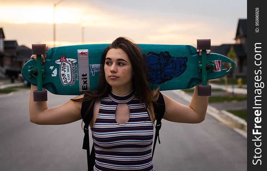 A woman holding a longboard on her shoulders. A woman holding a longboard on her shoulders.