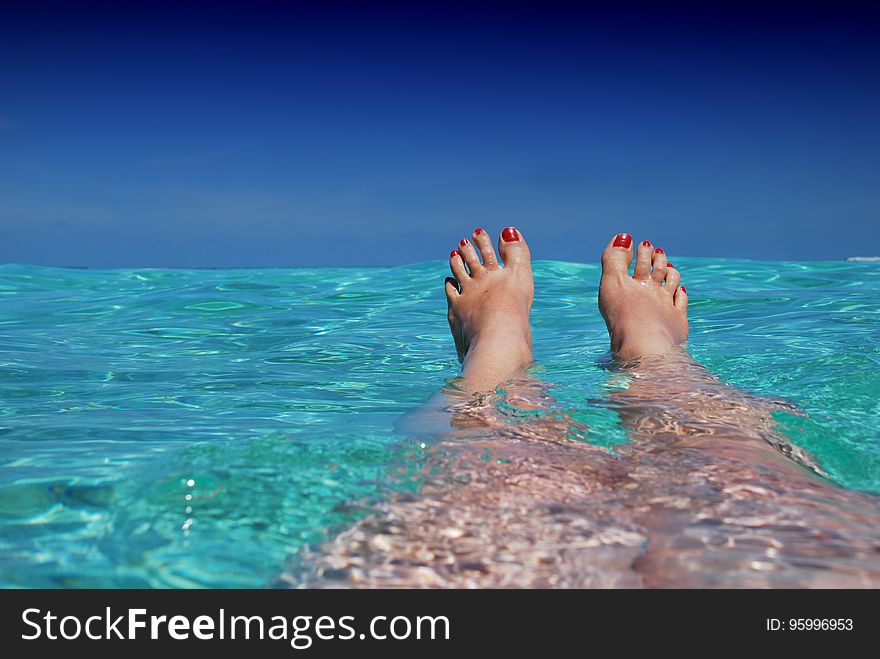 The feet of a woman floating in blue sea. The feet of a woman floating in blue sea.