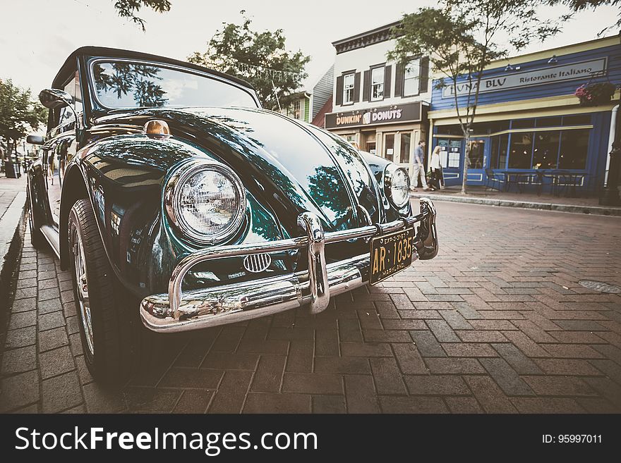 Vintage green car parked at curb on streets in front of shops. Vintage green car parked at curb on streets in front of shops.