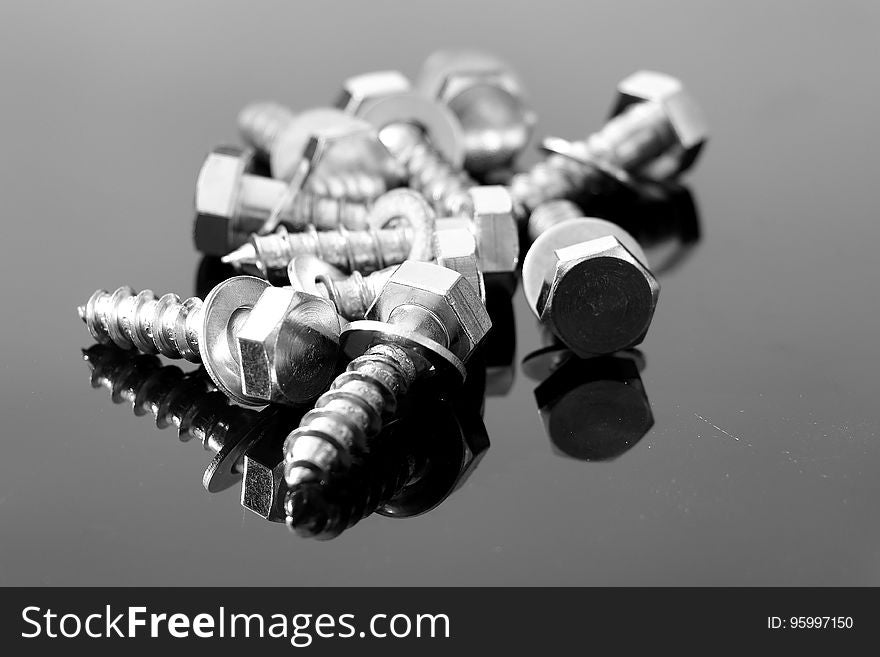 Close up of screws with washer on reflective surface in black and white. Close up of screws with washer on reflective surface in black and white.