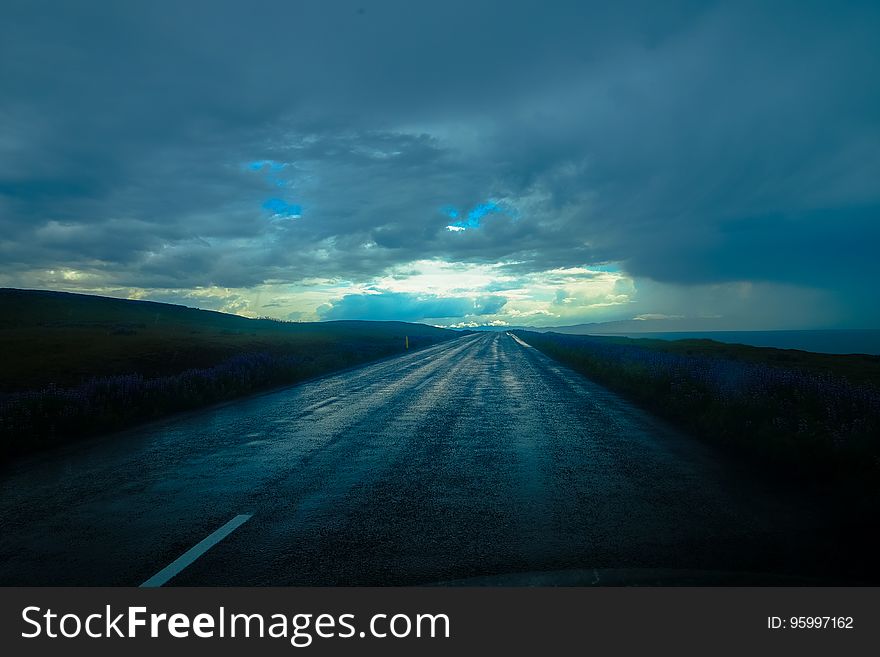 Empty roadway in countryside with blue storm clouds in sky. Empty roadway in countryside with blue storm clouds in sky.