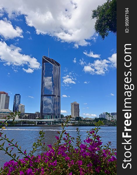 Exterior of steel and glass skyscraper in city skyline along waterfront against blue skies on sunny day. Exterior of steel and glass skyscraper in city skyline along waterfront against blue skies on sunny day.