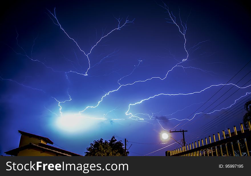 Dramatic lightning bolts in blue night sky above modern buildings. Dramatic lightning bolts in blue night sky above modern buildings.