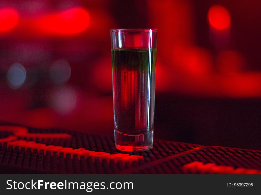 A shot glass with liquor on the bar counter. A shot glass with liquor on the bar counter.