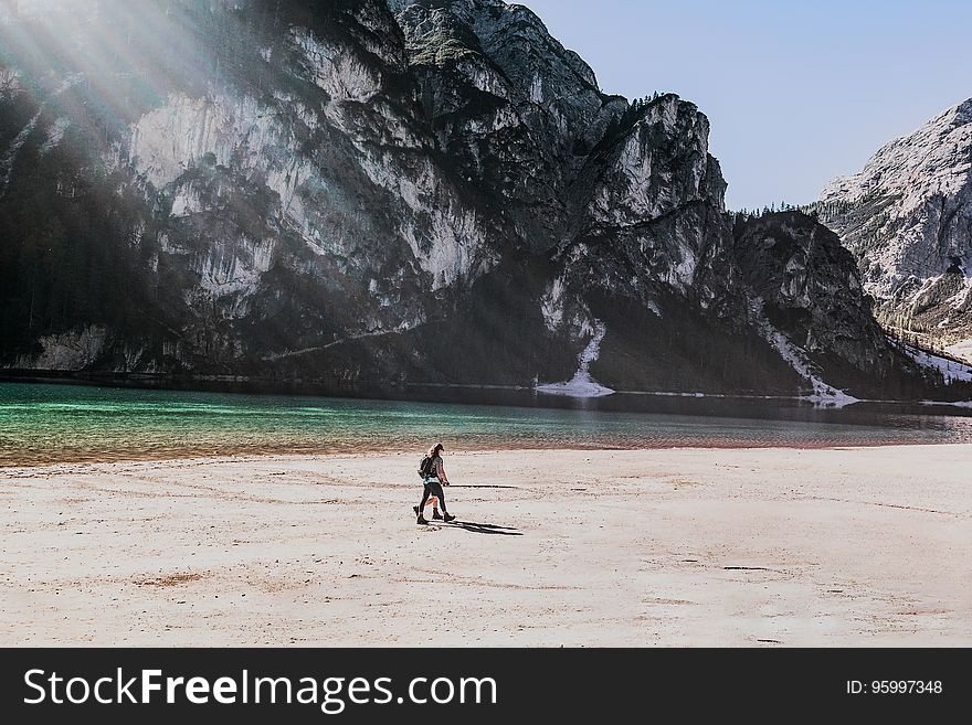 A hiker walking on a sandy beach with mountains in the distance. A hiker walking on a sandy beach with mountains in the distance.