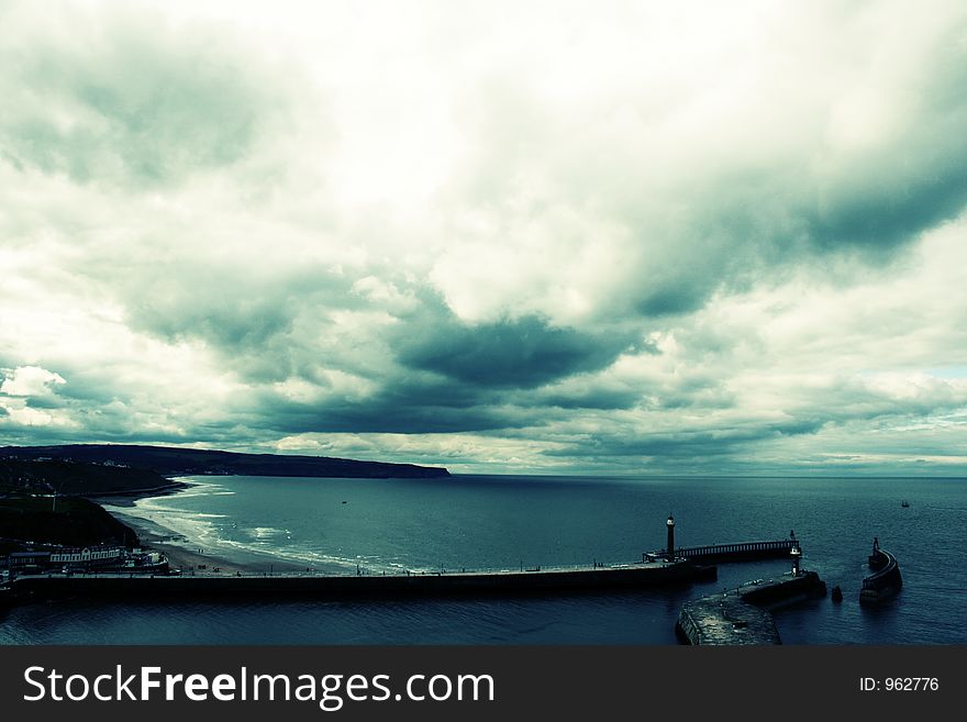 Clouded Whitby Bay, showing sea, beach, cliffs, pier and lighthouses. Clouded Whitby Bay, showing sea, beach, cliffs, pier and lighthouses.