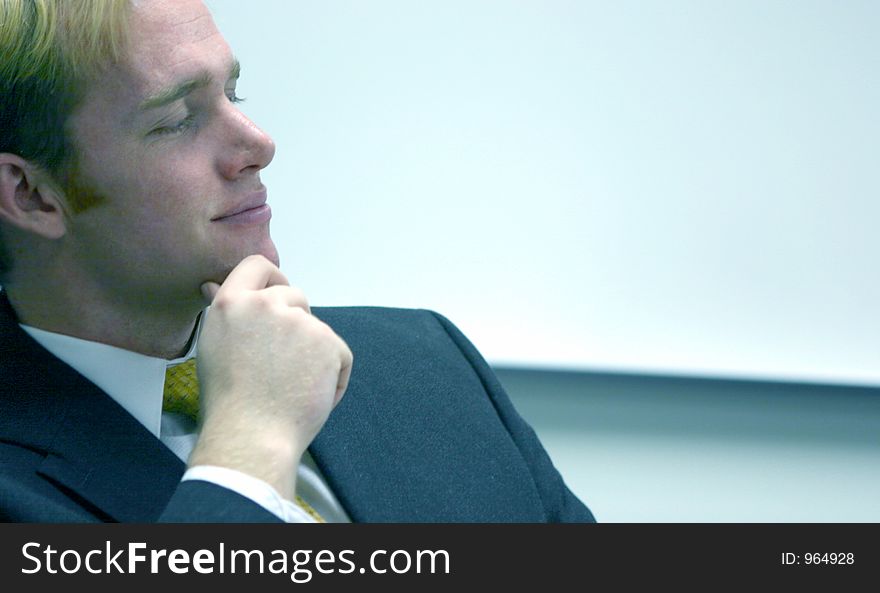 Blond hair blue eye businessman holds hand up next to his chin and smiles. Blond hair blue eye businessman holds hand up next to his chin and smiles