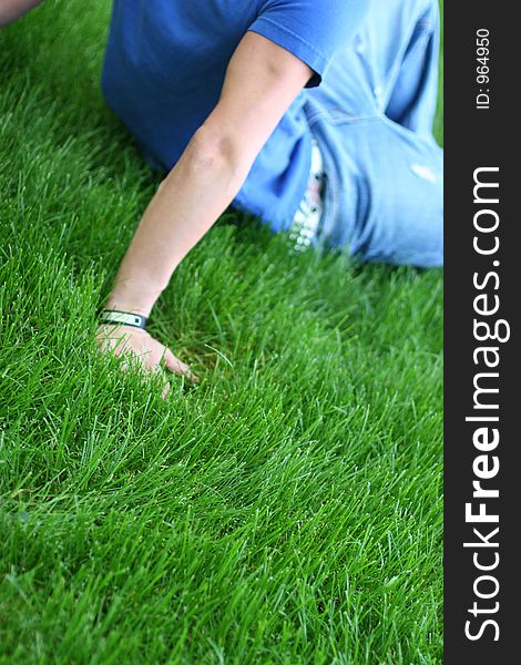Younger man is sitting in grass with his arms holding him up. Younger man is sitting in grass with his arms holding him up