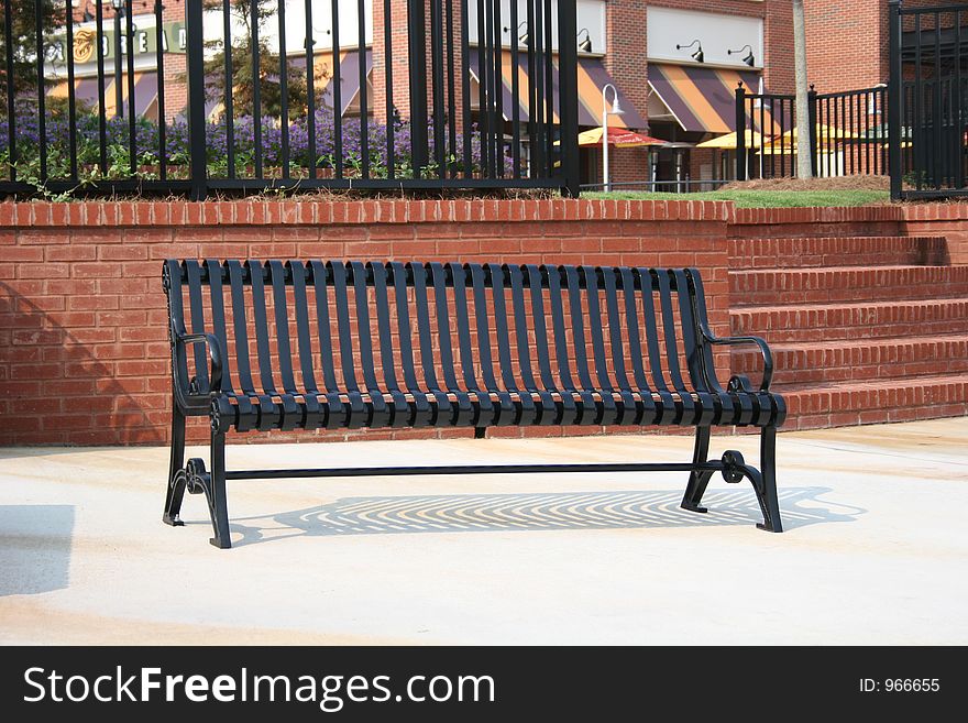 Metal bench in front of brick wall. Metal bench in front of brick wall