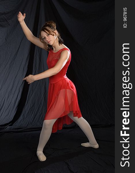 A bellerina posed standing in a red costume. A bellerina posed standing in a red costume