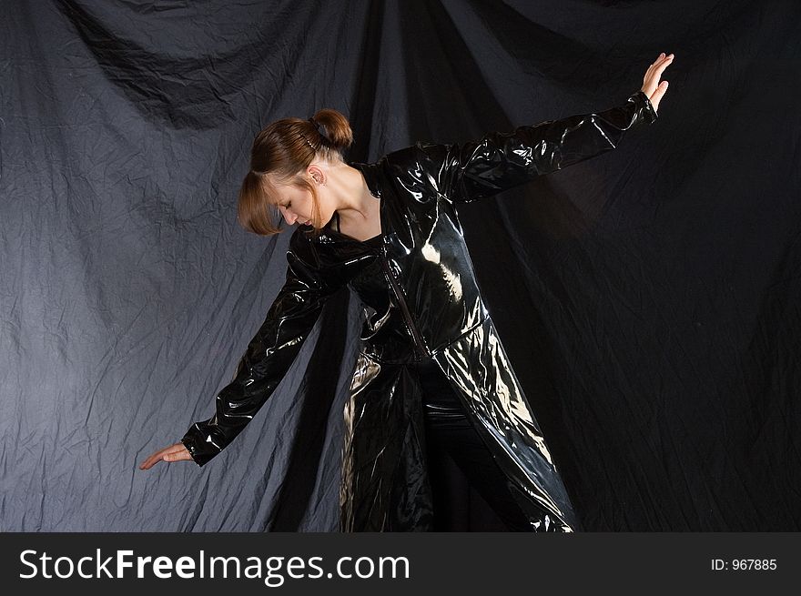 A dancer posed in black vinyl and holding a jazz pose. A dancer posed in black vinyl and holding a jazz pose