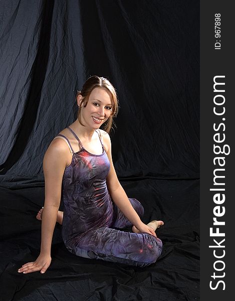 A modern dancer posed sitting, looking into the camera smiling. A modern dancer posed sitting, looking into the camera smiling