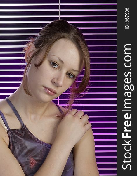 A serious portrait of a young woman woth verticle blind and a splash of purple in the background. A serious portrait of a young woman woth verticle blind and a splash of purple in the background