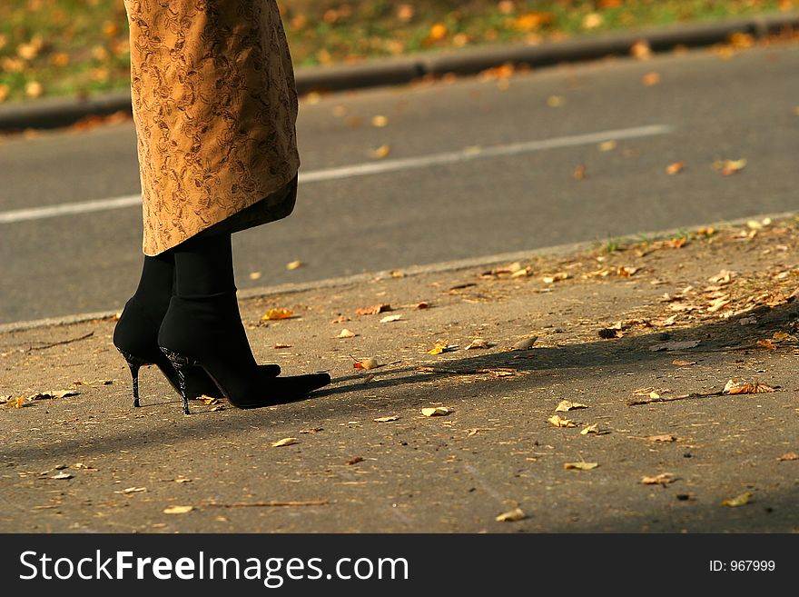 The image of female legs at edge of road. The image of female legs at edge of road