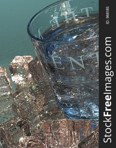 Light blue glass with ice cubes on a reflective surface