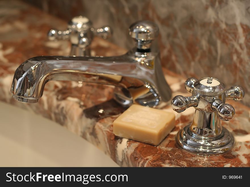 Luxury faucet with soap on marble background
