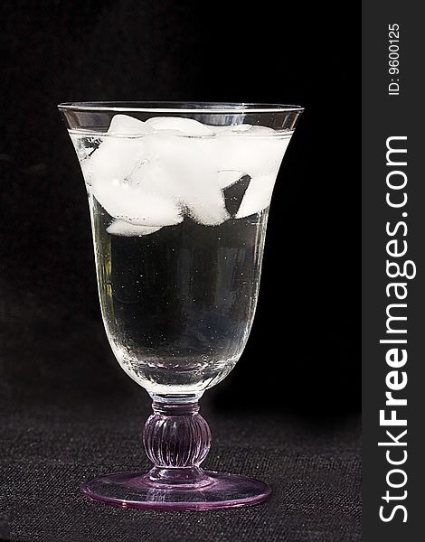 Glass of ice water with ice cubes on a black background. Glass of ice water with ice cubes on a black background